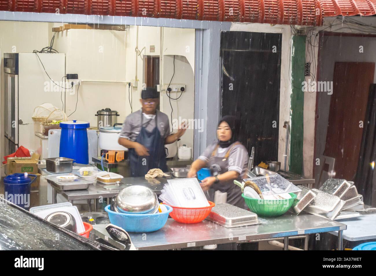 Starker Regenregen in Kuala Lumpur, Mitarbeiter organisieren Versorgungseinrichtungen in einem Café in Malaysia Stockfoto