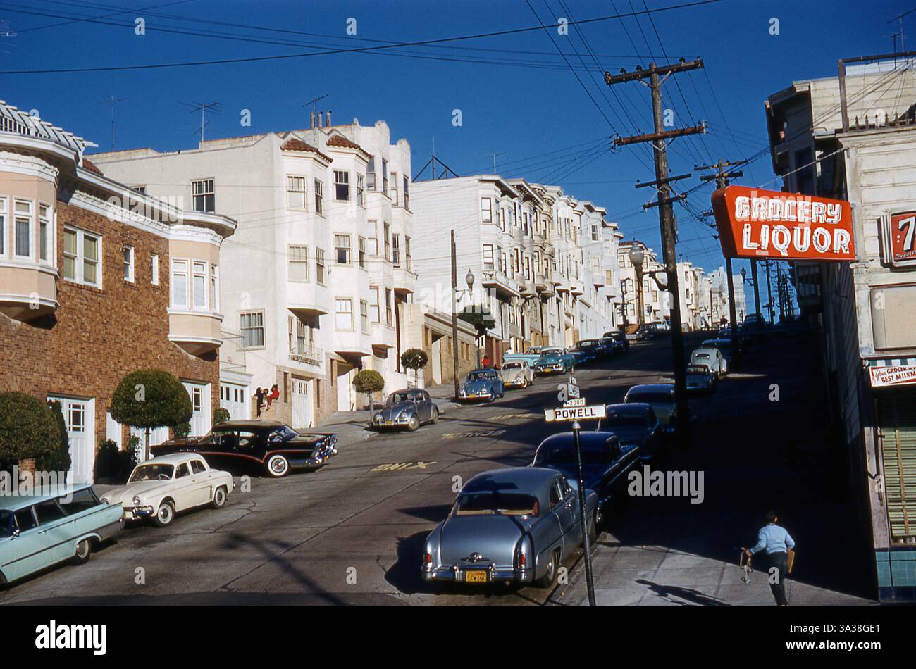 Junge, der Rollschuhe auf der Powell Street in San Francisco trägt. 1959. Zu den geparkten Autos gehören Volkswagen Beetle, Mercury 1951, Buick Roadmaster und Renault Dauphine Stockfoto