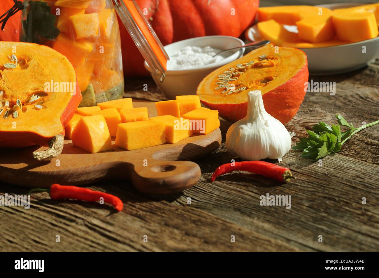 Marinierte Einmachgläser. Hausgemachte Kürbisgurken in Orangenform mit roten, heißen Chili-Paprika, frischer Petersilie und Gewürzen Stockfoto