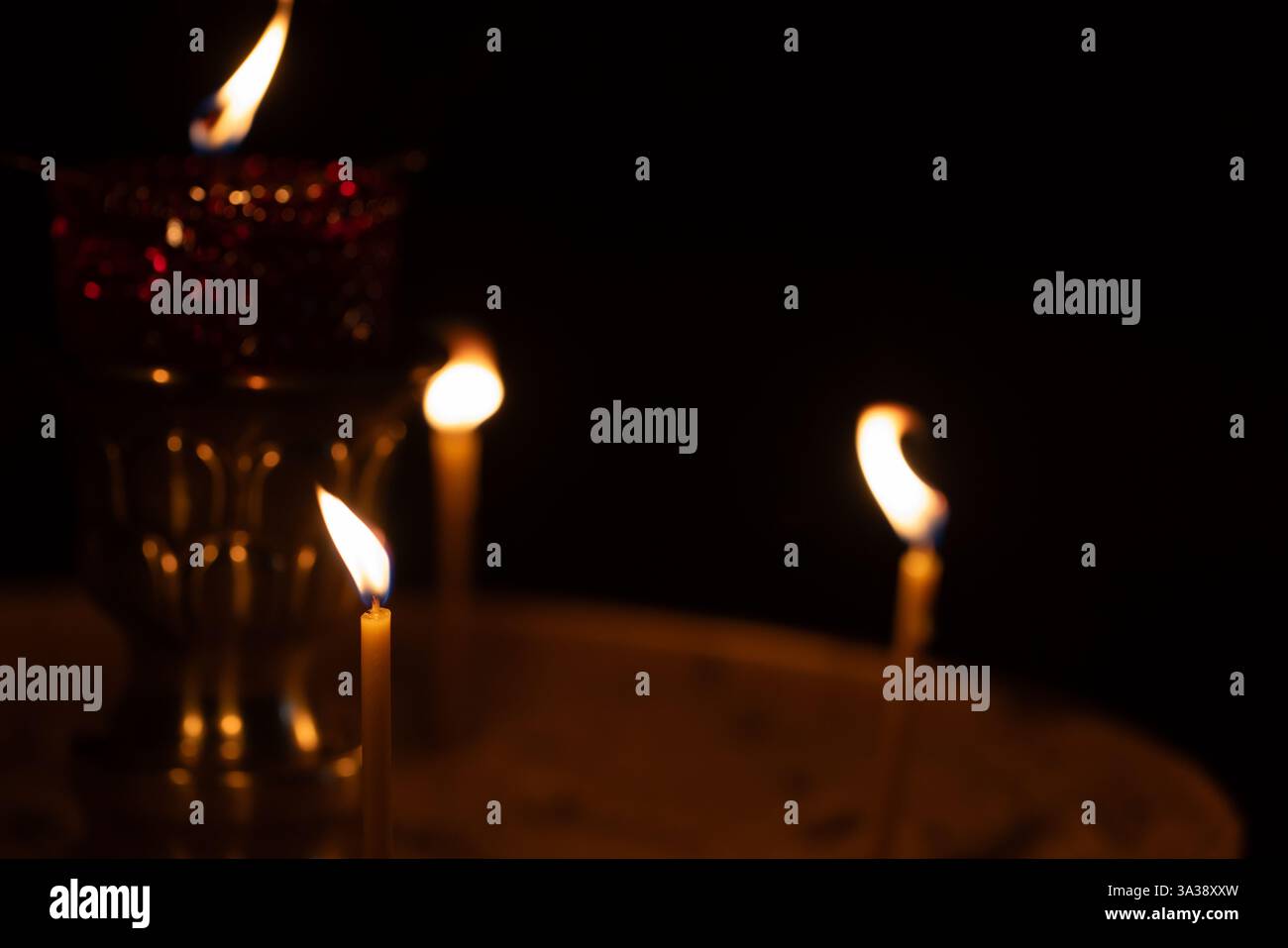 Wenige Kerzen leuchten schwach in einer ruhigen, religiösen Umgebung und schaffen ein Ambiente der Spiritualität und Ruhe. Selektiver Weichfokus Stockfoto