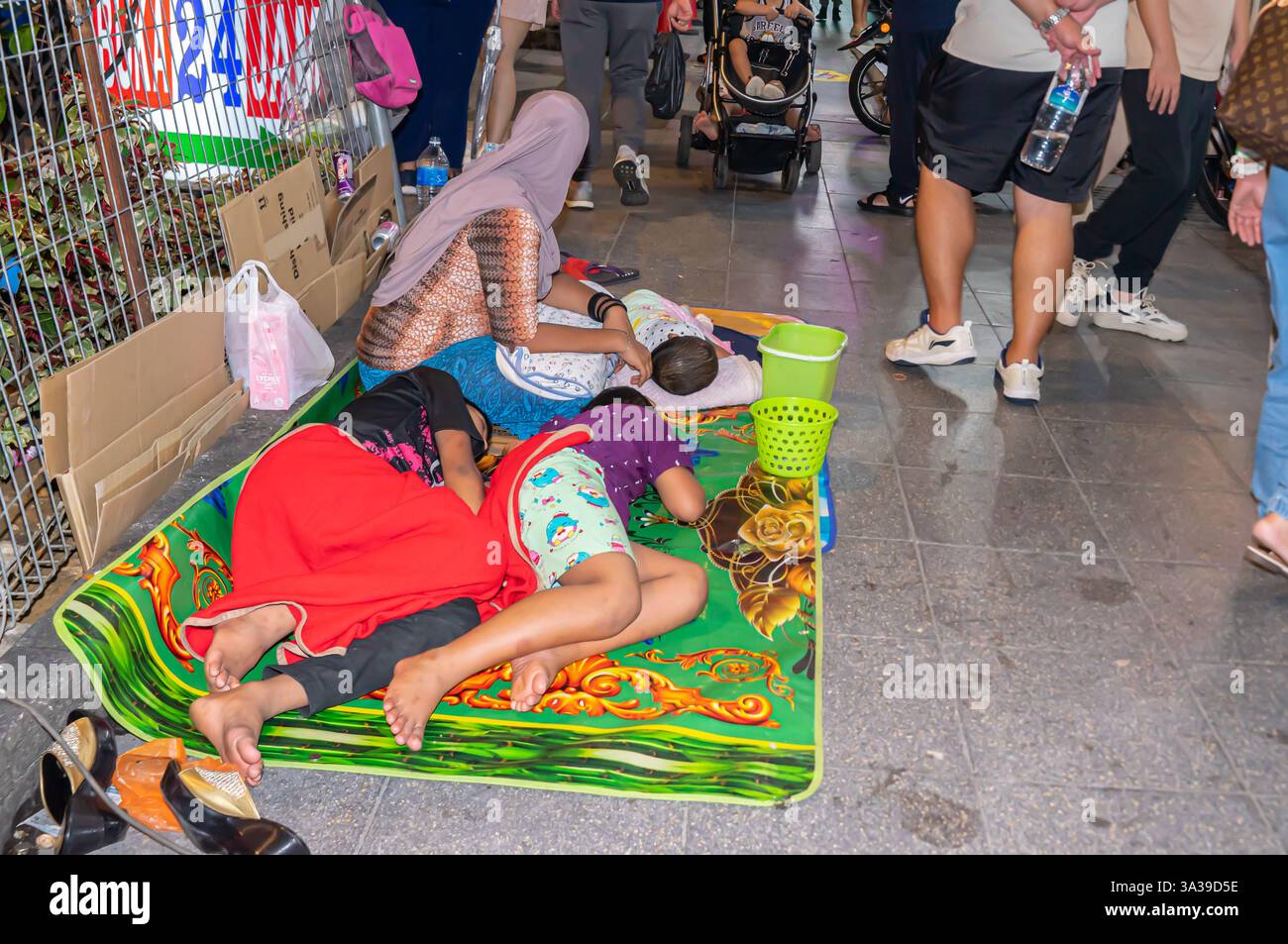 Obdachlose Familie, schlafend auf einer Matte auf der Straße, Bettlöffel, Zentrum von Kuala Lumpur, Malaysia Stockfoto