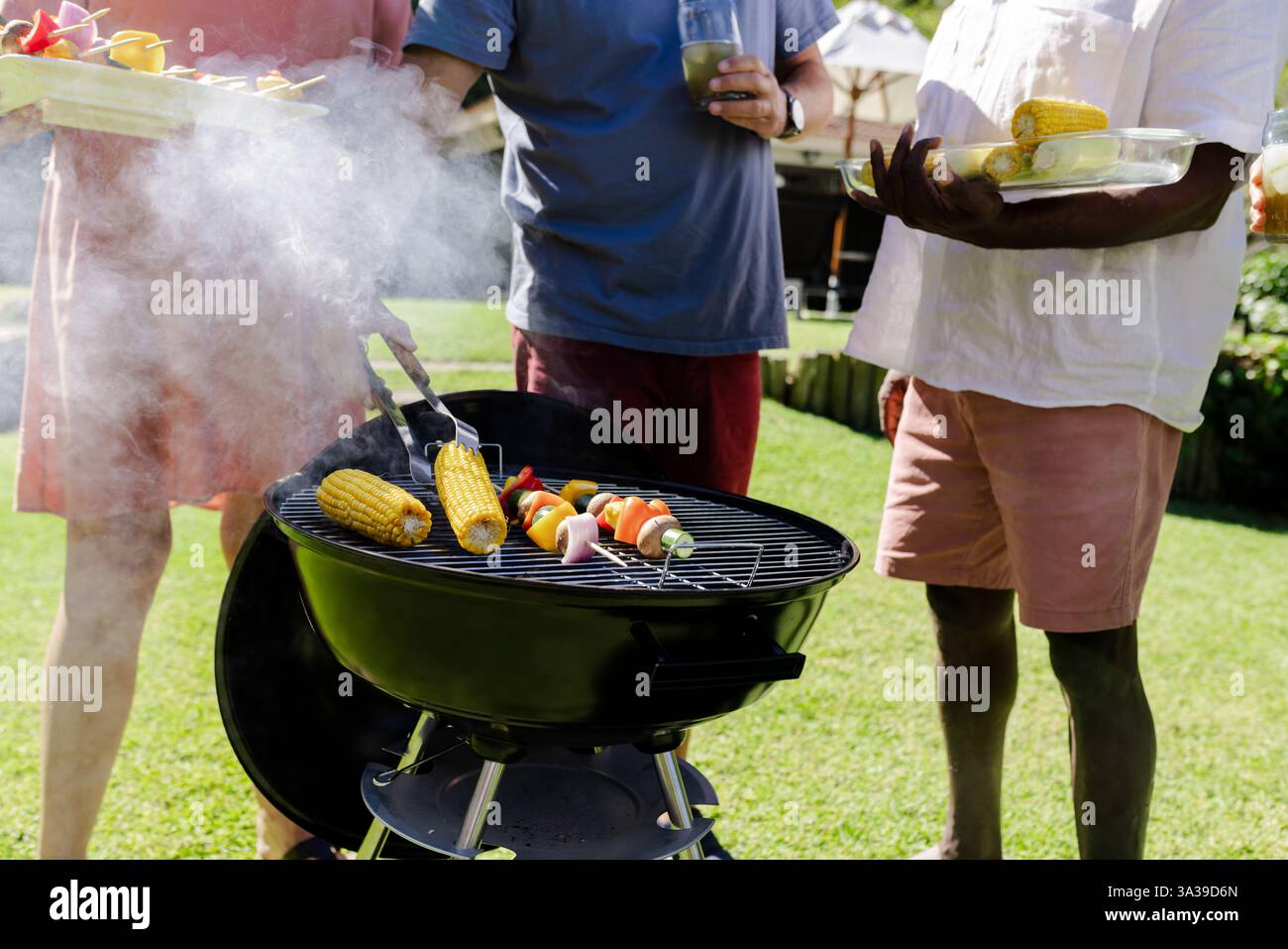 Grillen Sie Gemüse und Mais auf dem Grill, Seniorenfreunde genießen Treffen im Freien Stockfoto