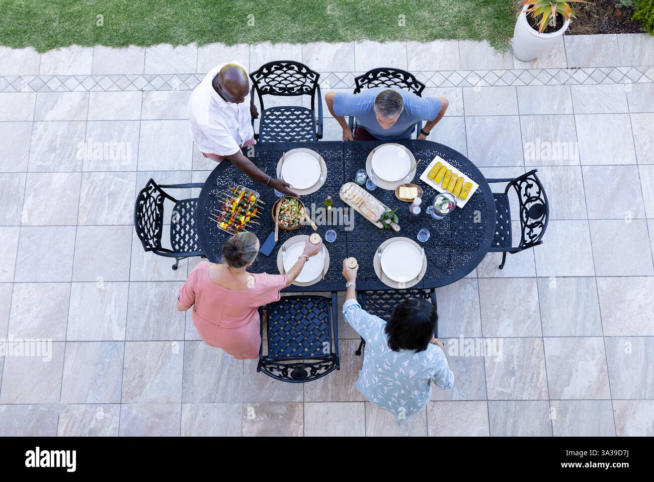 Eine Gruppe verschiedener älterer Freunde genießt ein Essen im Freien und legt sich einen Tisch mit köstlichen Speisen und Getränken Stockfoto