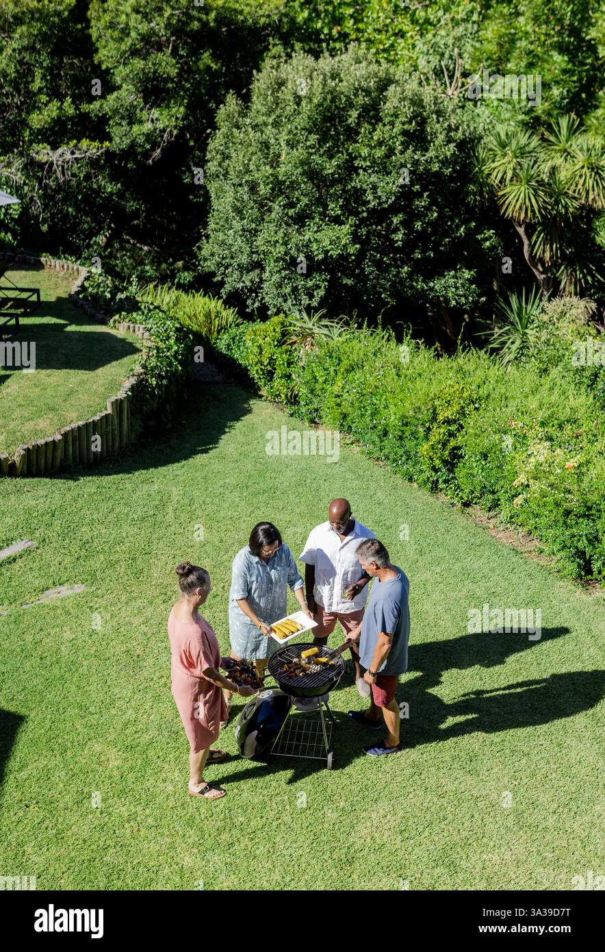 Gruppe von Seniorenfreunden, die im Freien Barbecue in üppig grünem Garten genießen, Kopierraum Stockfoto