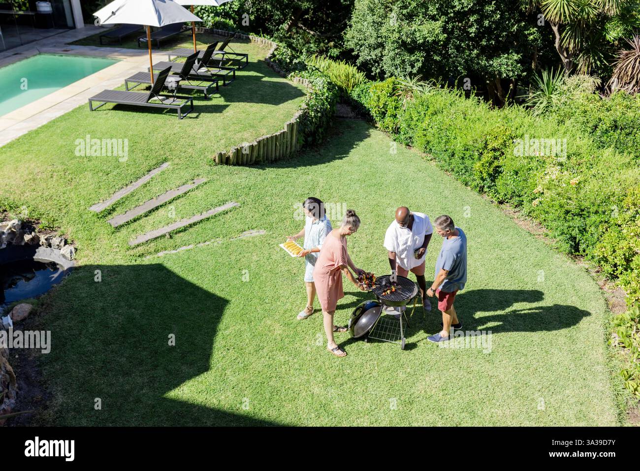 Grillen und Treffen, Seniorenfreunde grillen gemeinsam im sonnigen Hinterhof Stockfoto