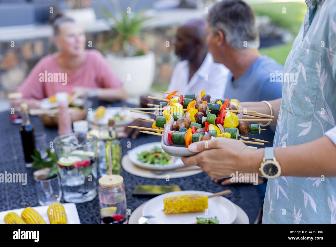 Es werden bunte Gemüsespieße bei einem Treffen im Freien serviert, bei dem Seniorenfreunde essen Stockfoto