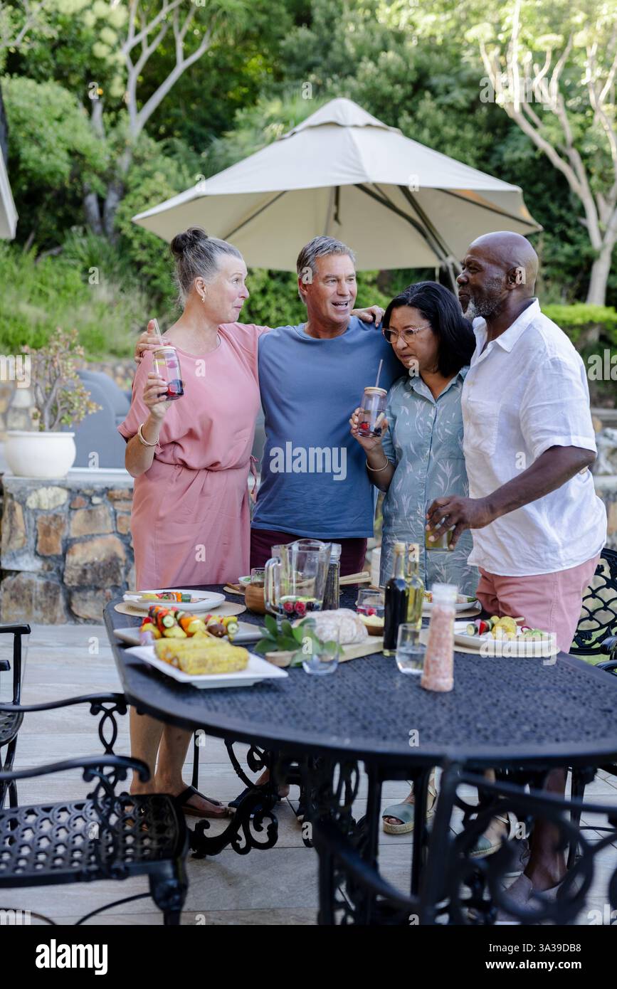 Gruppe von Seniorenfreunden, die sich bei Getränken und Speisen im Freien treffen und gemeinsam lächeln Stockfoto