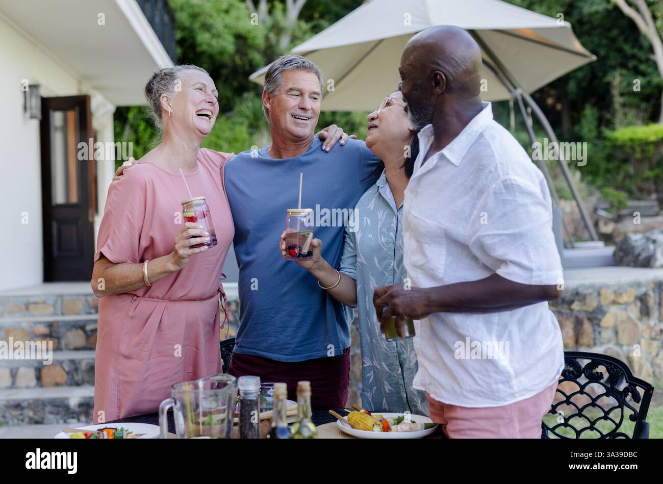 Ältere Freunde genießen Treffen im Freien, Lachen und Erfrischungsgetränke Stockfoto