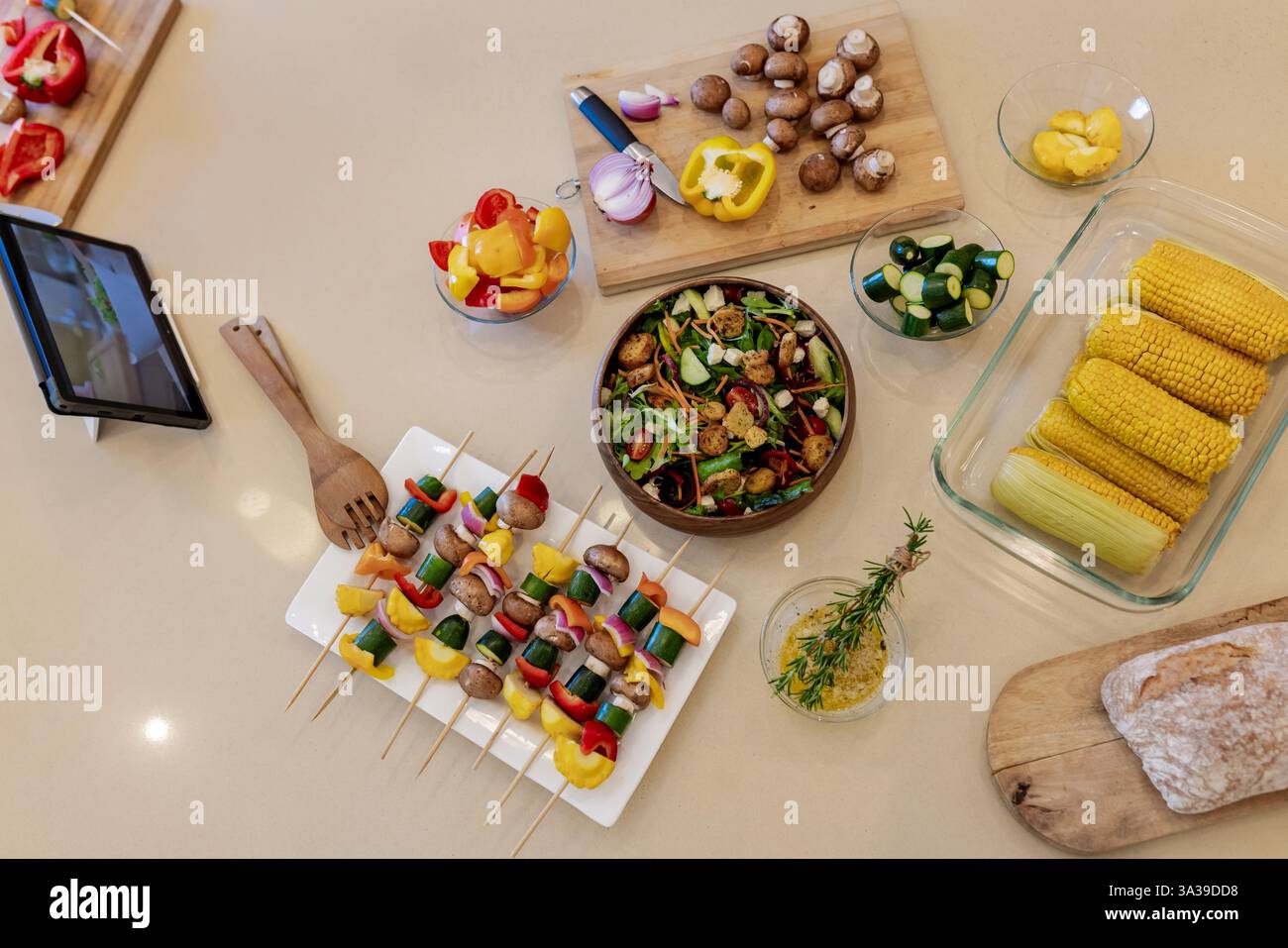 Bunte Gemüsespieße und frischer Salat mit Mais und Brot auf der Küchenzeile Stockfoto