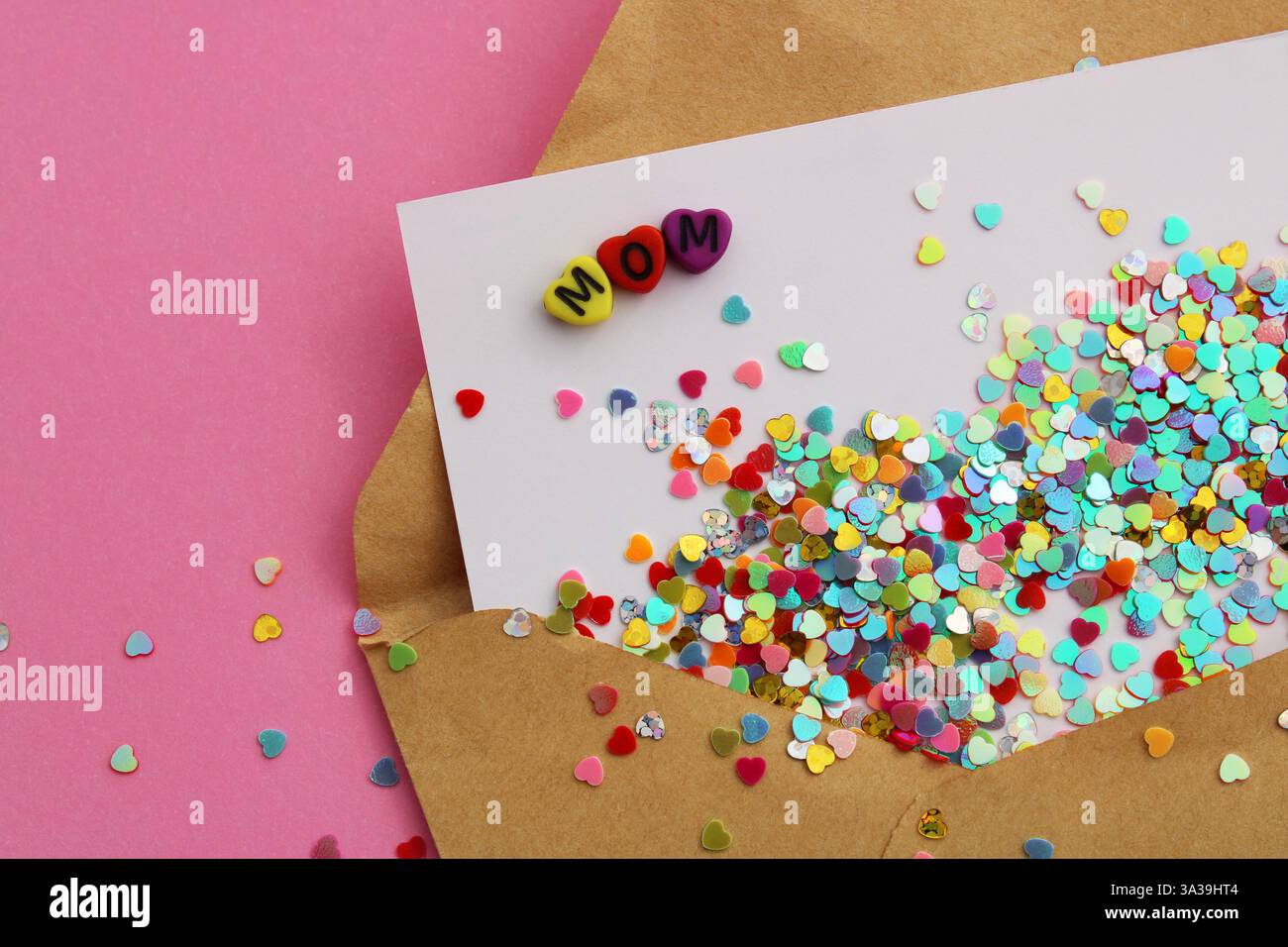Das Wort MOM auf einer Karte voller bunter Herzen, die aus einem Umschlag kommen Stockfoto
