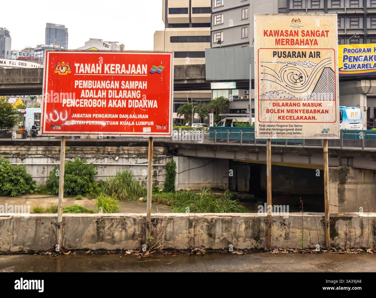 Warnschilder in Malay, KL Malaysia. „Regierungsland. Das Abwerfen von Müll ist verboten. Eindringlinge werden strafrechtlich verfolgt."; "sehr gefährliches Gebiet..." Stockfoto