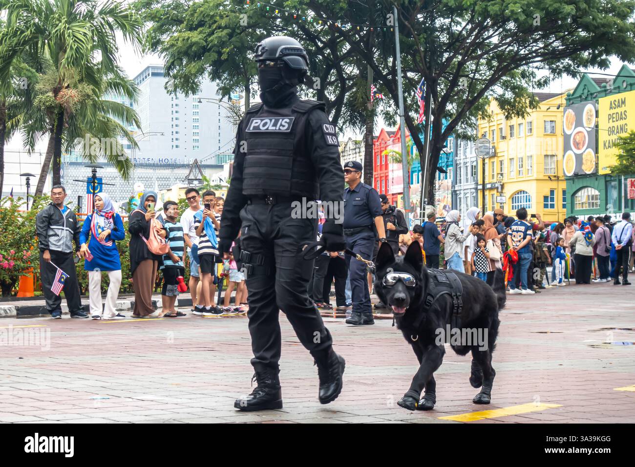 Ein Polizeibeamter in voller Uniform, ein schwarzer Hund, ein Polizeihund oder eine K9-Einheit. Vertreter der malaysischen Polizei, National Day Parade, Melaka Malaysia Stockfoto
