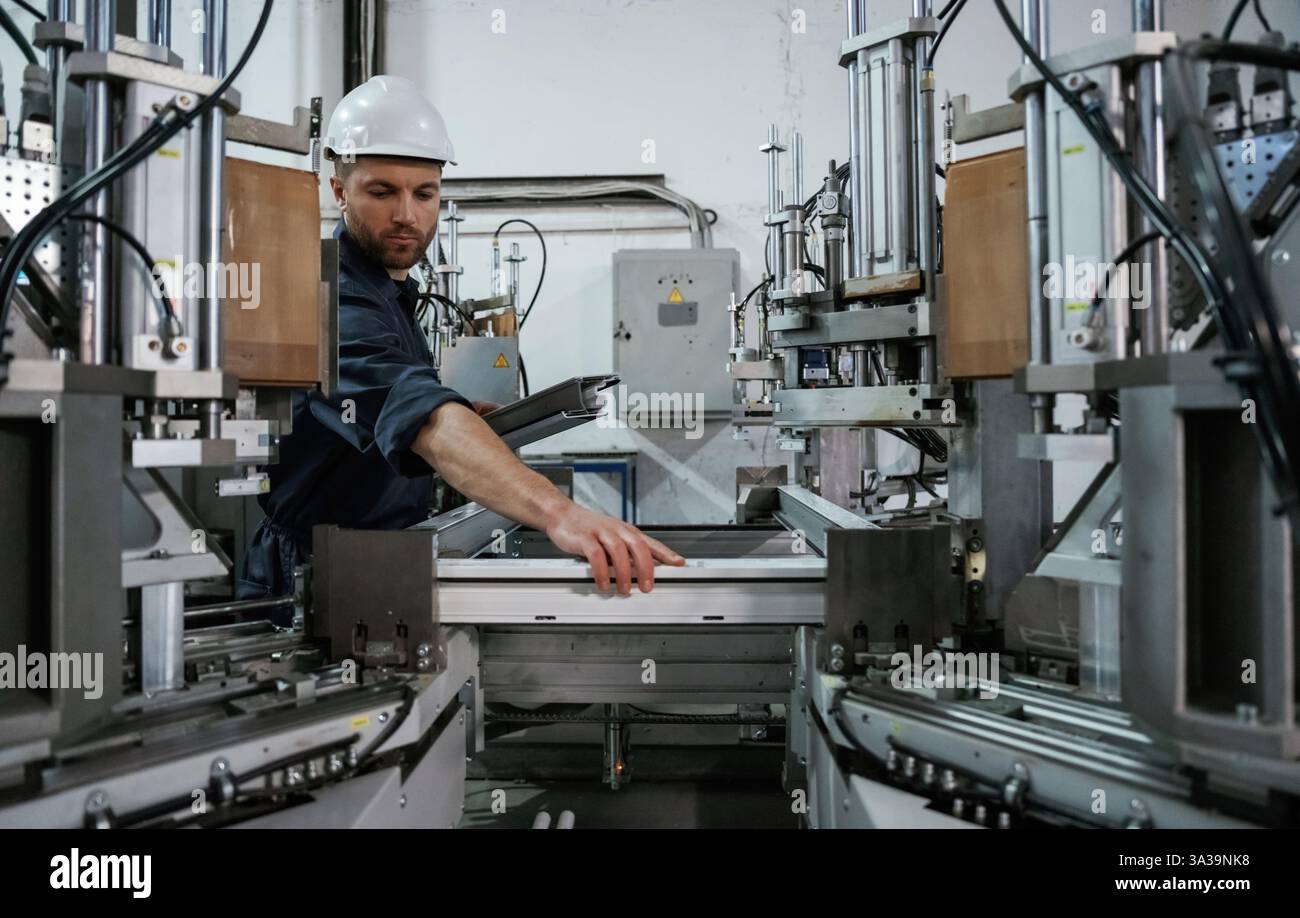 Prüfung der Materialqualität, Kontrolle. Fabrikarbeiter ist mit Schutzhelm drinnen. Stockfoto