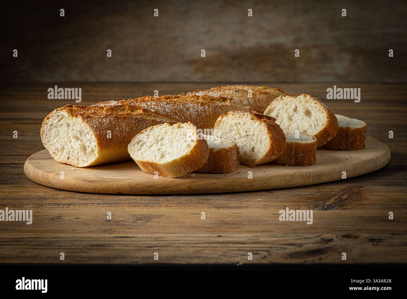 Frisch gebackenes Baguette-Brot auf rustikalem Holzküchentisch in der Bäckerei Stockfoto