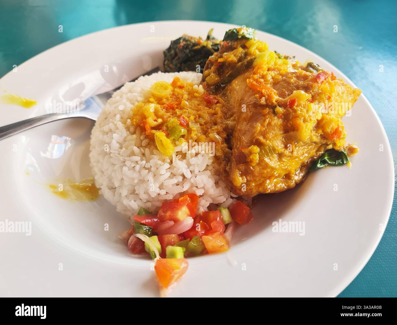 Indonesisches Manadonesisches Essen Nasi Ayam Woku mit Tumis Daun Pepaya und Sambal Dabu-Dabu. Stockfoto