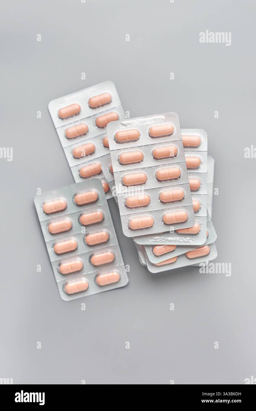 Gestapelte hellbraune Farbtabletten oder Pillen in Silberfolie Rückseite Blisterpackungen isolierter grauer Hintergrund, Pakete von Medikamenten, weiche Fokus Stockfoto