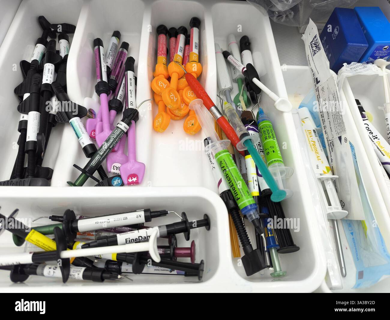 Verschiedene Zahnspritzen und Materialien in organisierten Tabletts für zahnärztliche Eingriffe. Stockfoto