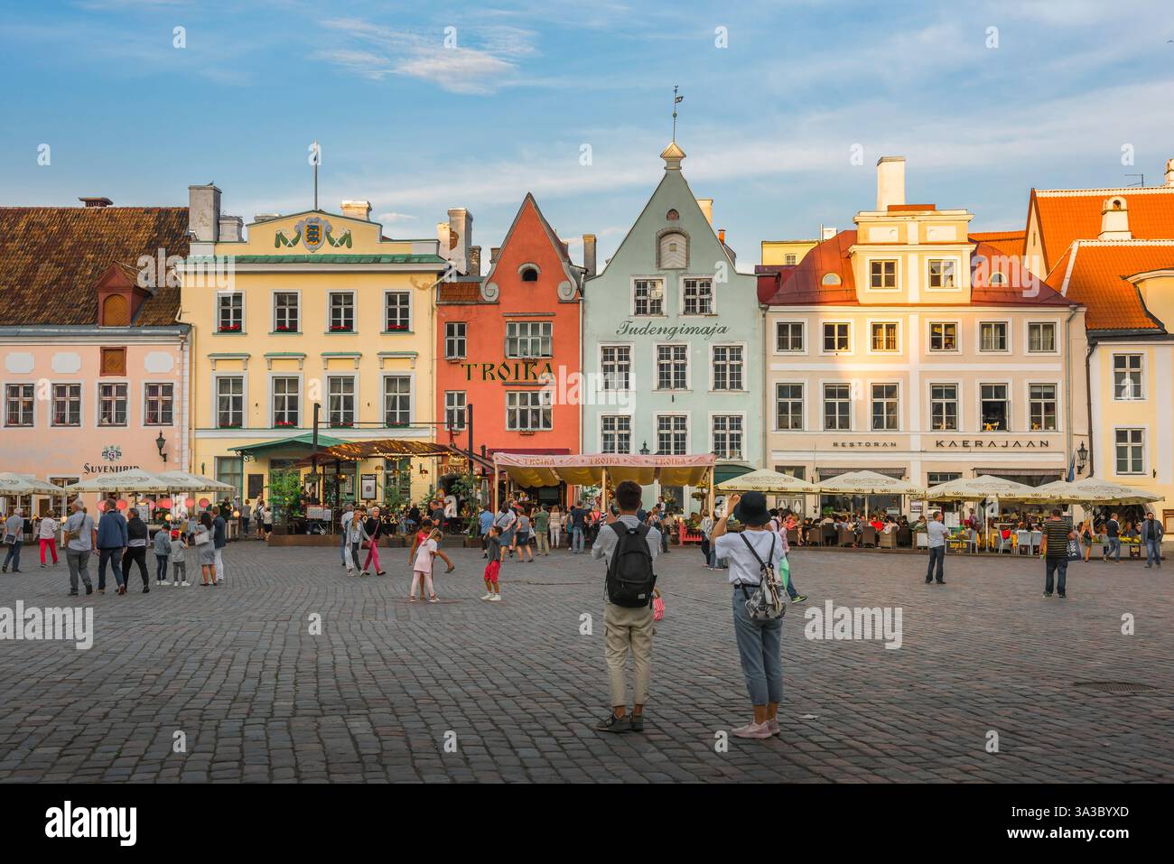 Baltikum Staatsreise, Blick im Sommer auf zwei junge Touristen, die den farbenfrohen Rathausplatz in der mittelalterlichen Altstadt in Tallinn, Estland, besuchen. Stockfoto