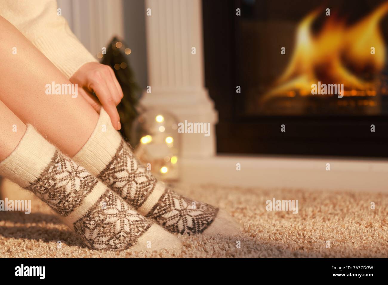 Frau in warmen Socken, die zu Hause am Kamin liegt, Nahaufnahme. Leerzeichen für Text Stockfoto