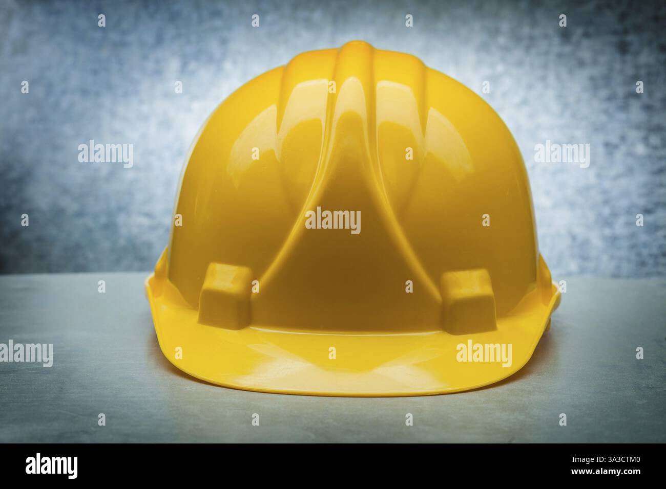 Gelber Konstruktionshelm auf metallischem Hintergrund, Nahansicht von vorne Stockfoto