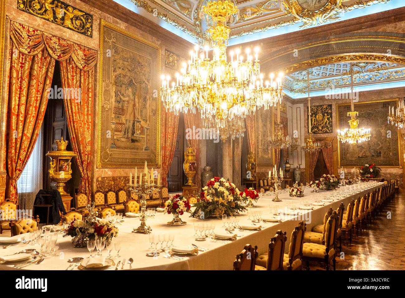 In der Mitte des Zimmers befindet sich ein langer Tisch mit einem Kronleuchter darüber Stockfoto