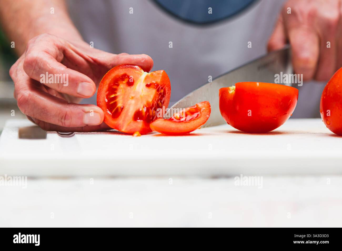 Hände eines Kochs, der frische Tomaten schneidet Stockfoto