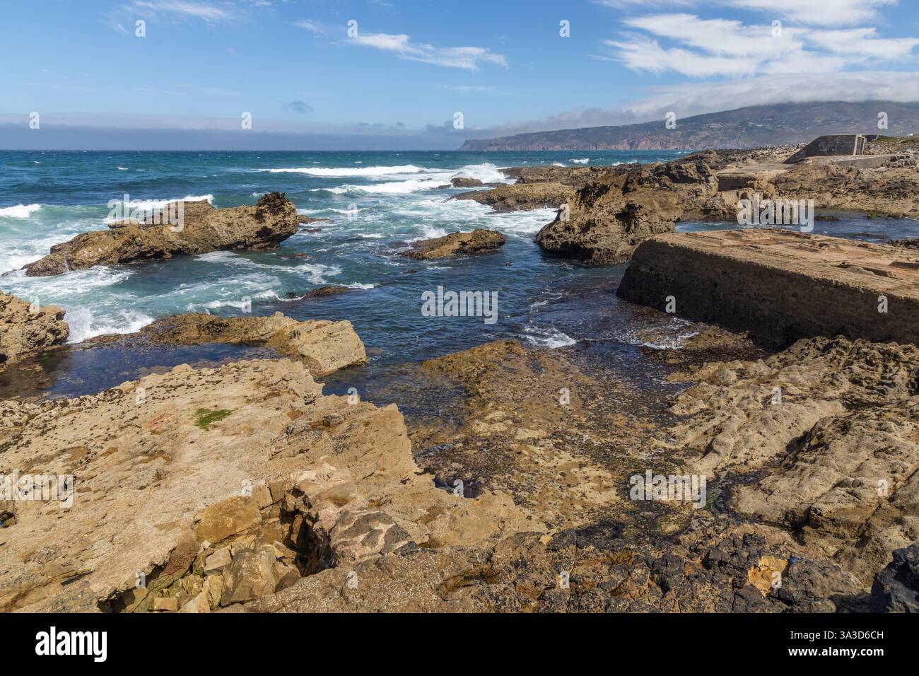 Felsküste mit dem atlantik und mit Bergen im Hintergrund in Cascais Portugal. Stockfoto