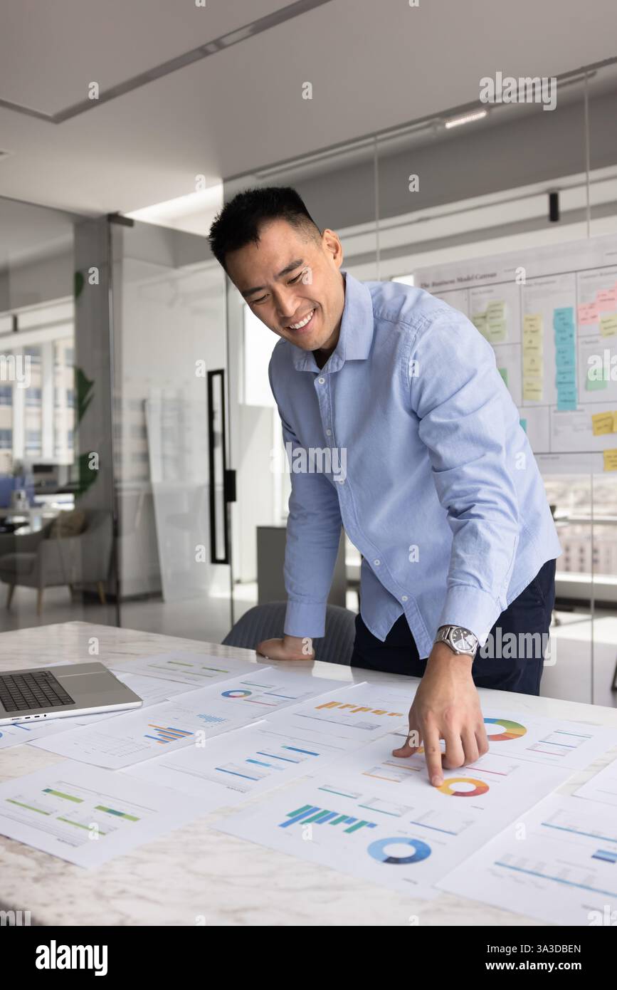 Glücklicher junger asiatischer Manager, der statistische Daten analysiert Stockfoto