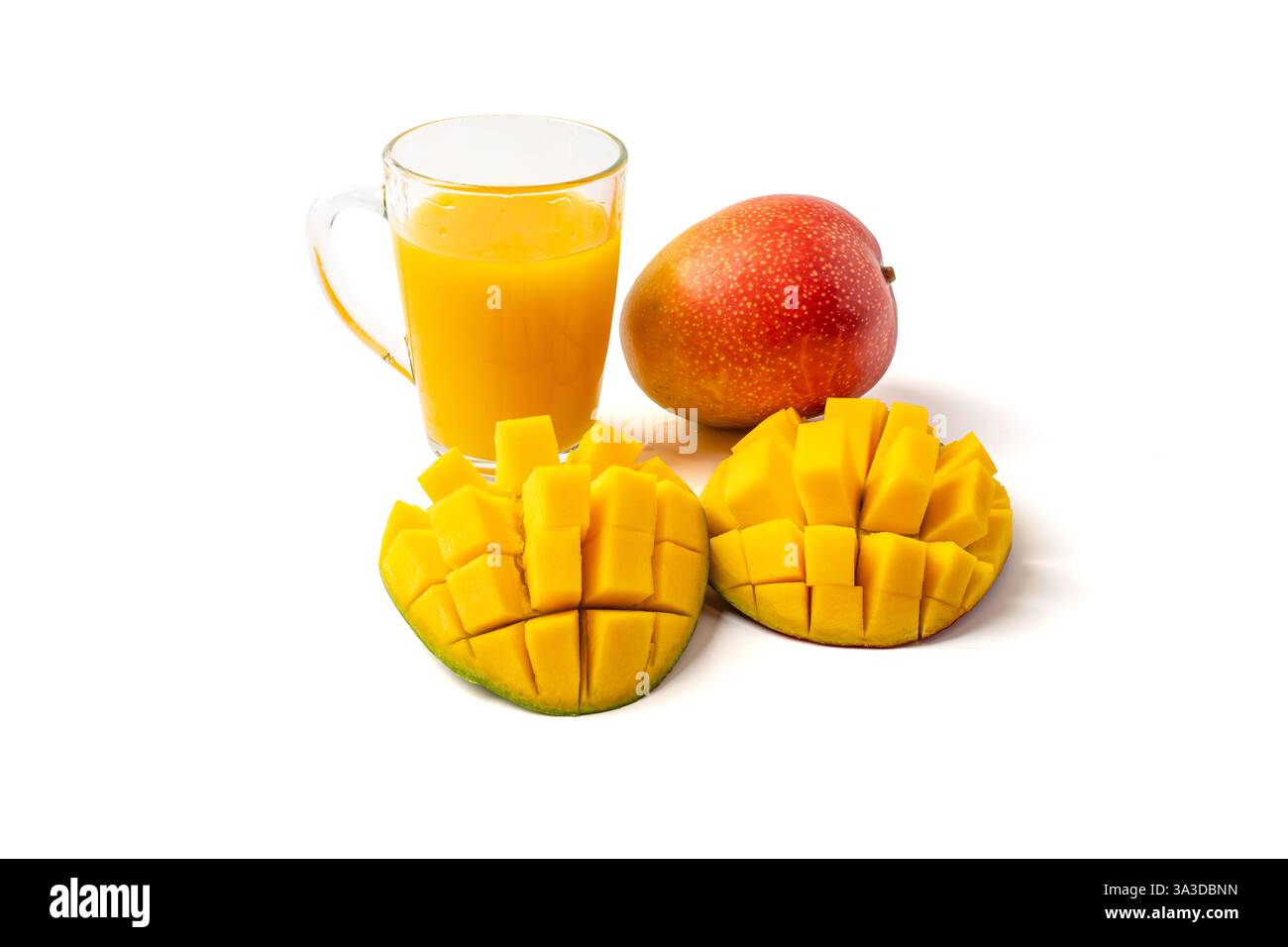 Ein Glas Saft wird neben die gehackte Mango auf weißem Hintergrund gelegt. Saft in transparentem Glas, und Mangos werden in kleine Stücke geschnitten Stockfoto