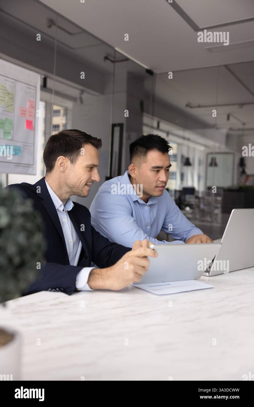 Zwei verschiedene männliche Geschäftskollegen arbeiten am Laptop zusammen Stockfoto