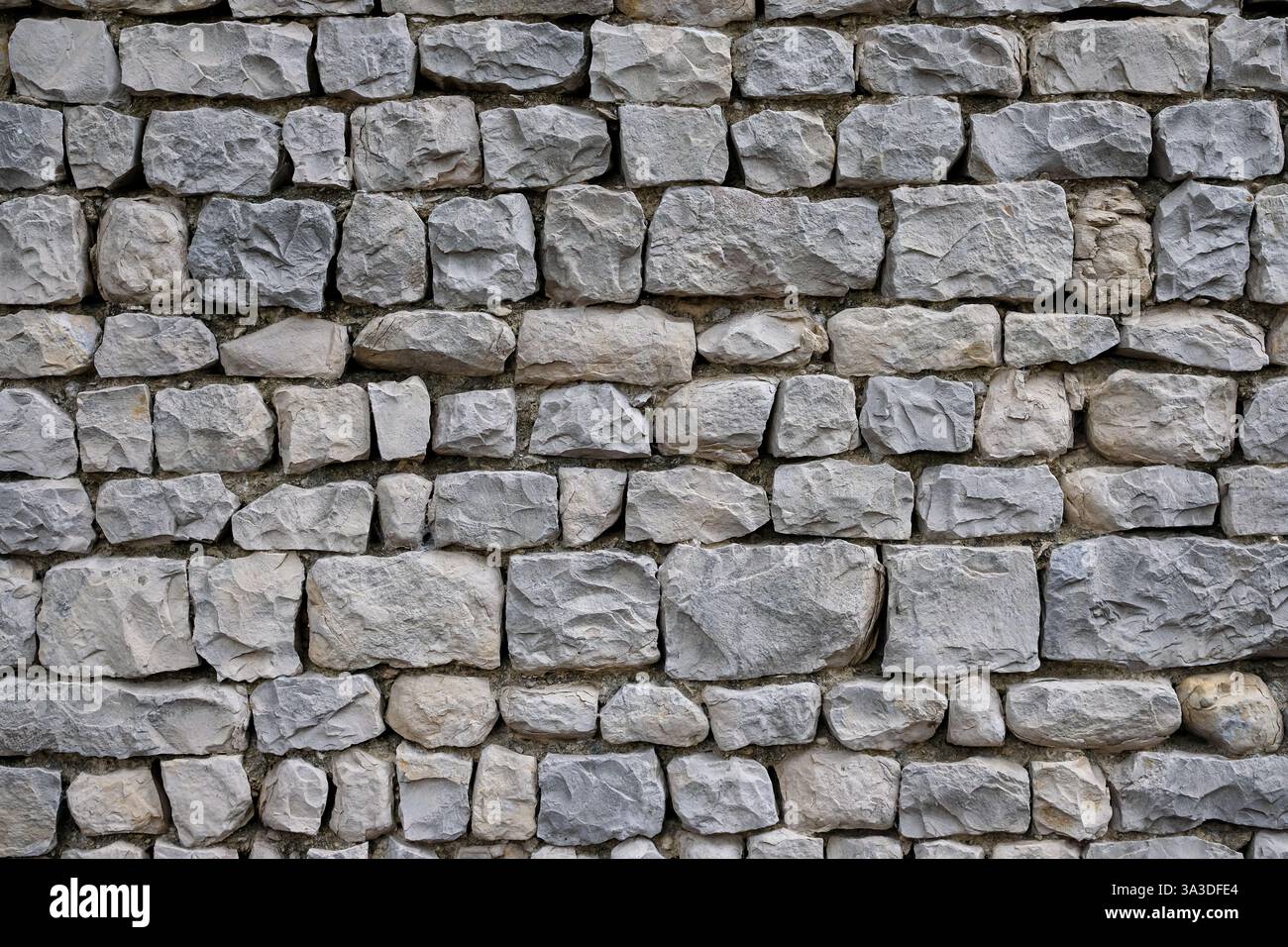 Die Steinmauer besteht aus unebenen, grob geschnittenen grauen Steinen. Detail des traditionellen Steinmauerwerks aus Südfrankreich im Dorf Seguret. Stockfoto