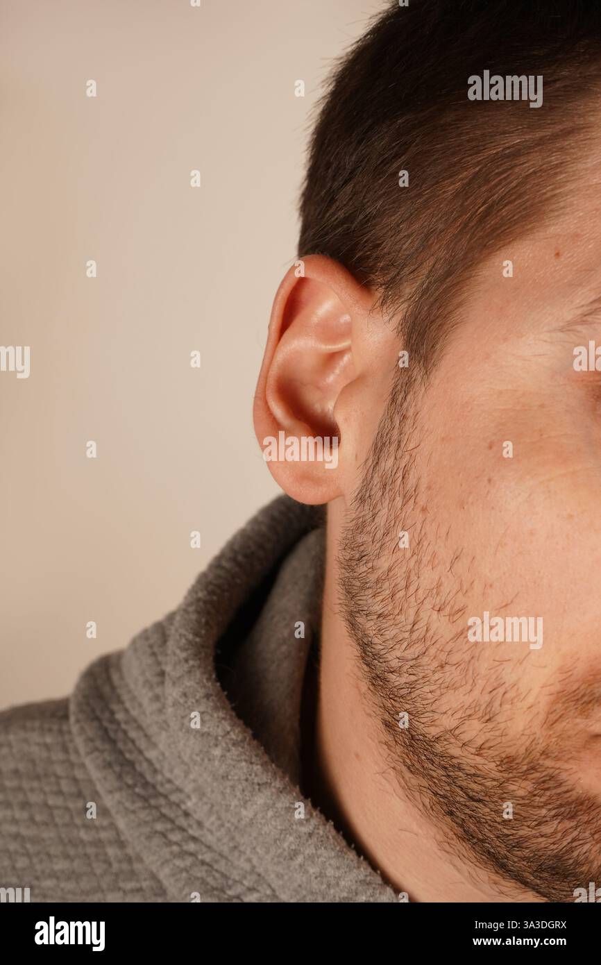 Ein minimalistisches Porträt, das die Schönheit der menschlichen Anatomie unterstreicht. Eine Nahaufnahme des Ohres eines Mannes mit natürlichen Linien und Hautstruktur. Das Bild Stockfoto