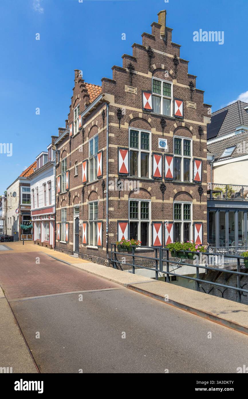 Gorinchem, Niederlande. 25. Juni 2024. Typische Häuser mit rot-weißen Fensterläden am Fenster in der befestigten Stadt Gorinchem entlang der Brücke an Stockfoto