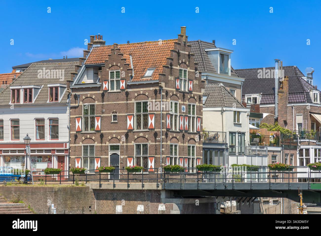 Gorinchem, Niederlande. 25. Juni 2024. Typische Häuser mit rot-weißen Fensterläden am Fenster in der befestigten Stadt Gorinchem entlang der Brücke an Stockfoto