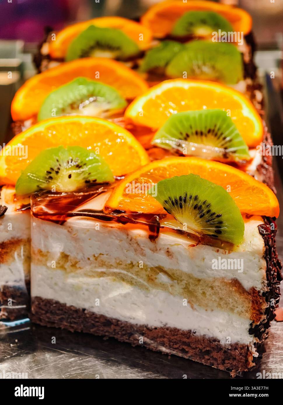 Lebendiger Kuchen mit Fruchtgarnitur mit Kiwi- und Orangenscheiben - erfrischendes Dessert mit cremiger Füllung - perfekt für Partys und Feiern - Gourmet-Gebäck mit frischen, saftigen Früchten Stockfoto