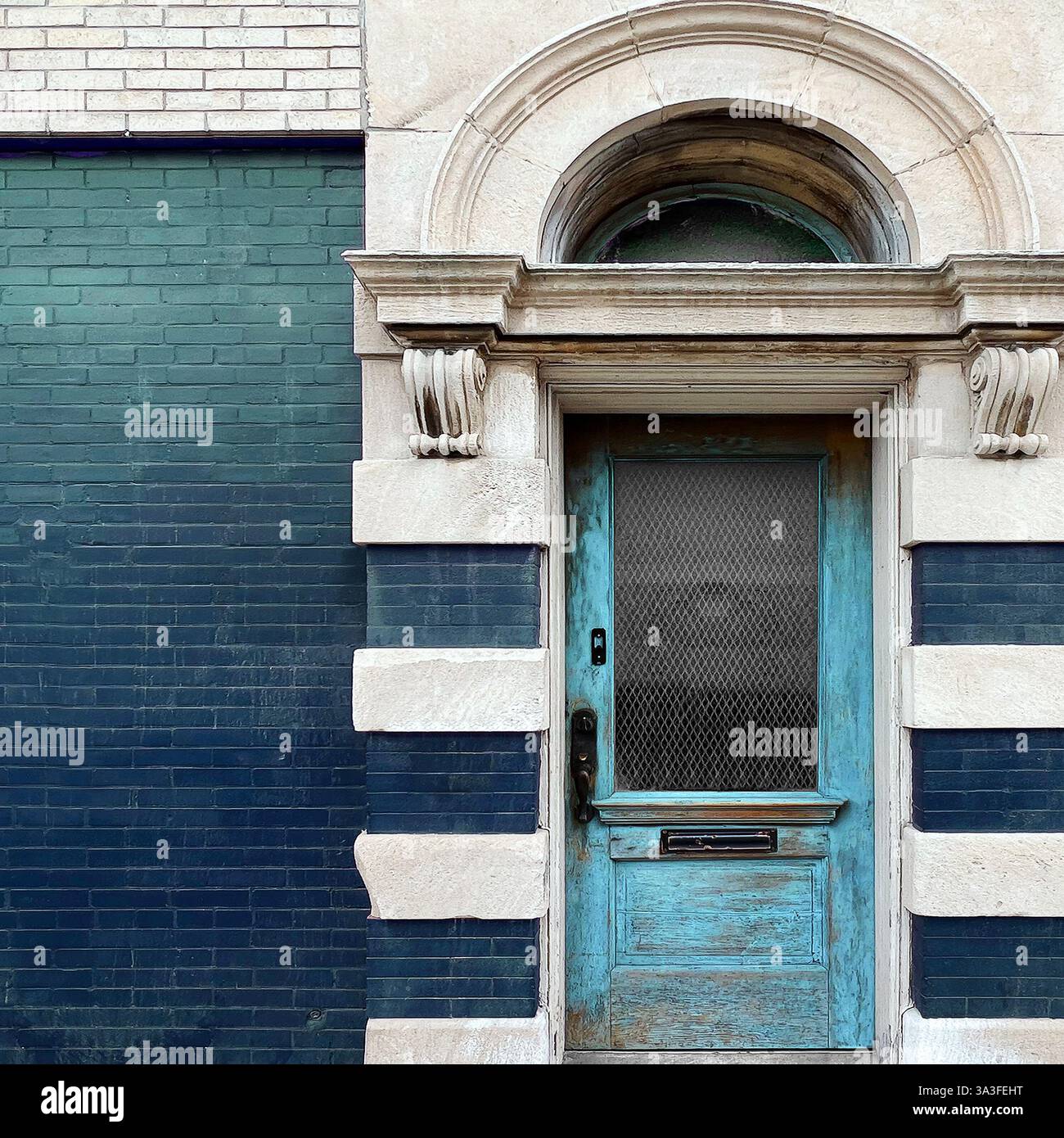 Hellblaue Holztür mit kunstvollen architektonischen Details in einer historischen Stein- und Ziegelfassade. - Smartphone-aufgenommenes Stockfoto