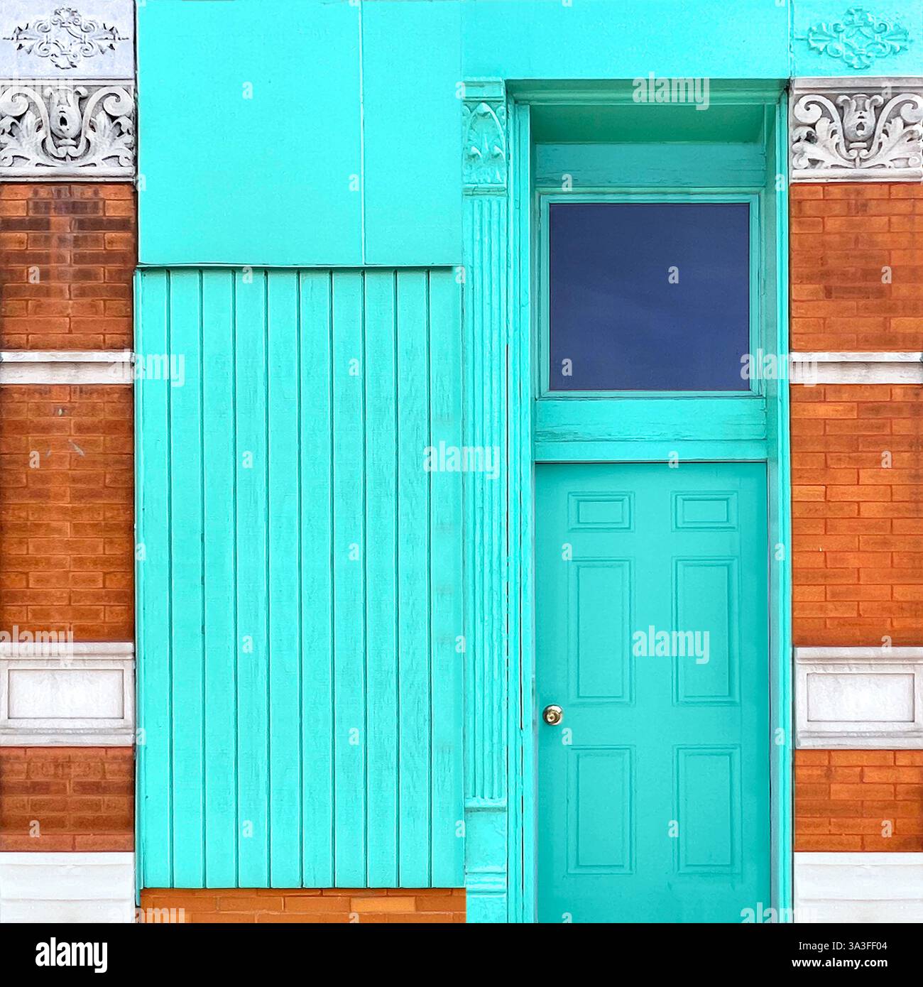 Türkisfarbene Tür vor einer orangen Ziegelfassade mit komplizierten weißen Architekturdetails, die einen lebhaften urbanen Kontrast darstellen. Stockfoto