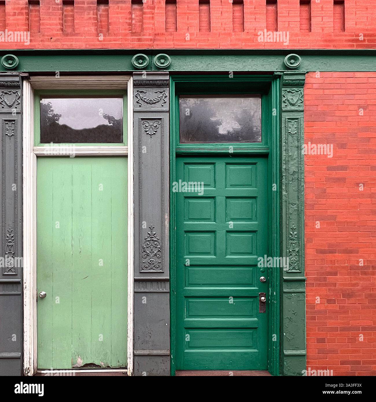 Zwei benachbarte Türen, die in ihrem Alter, aber durch Schatten geteilt sind, stehen als ruhiger Dialog in Chicago Brick. - Smartphone-aufgenommenes Stockfoto