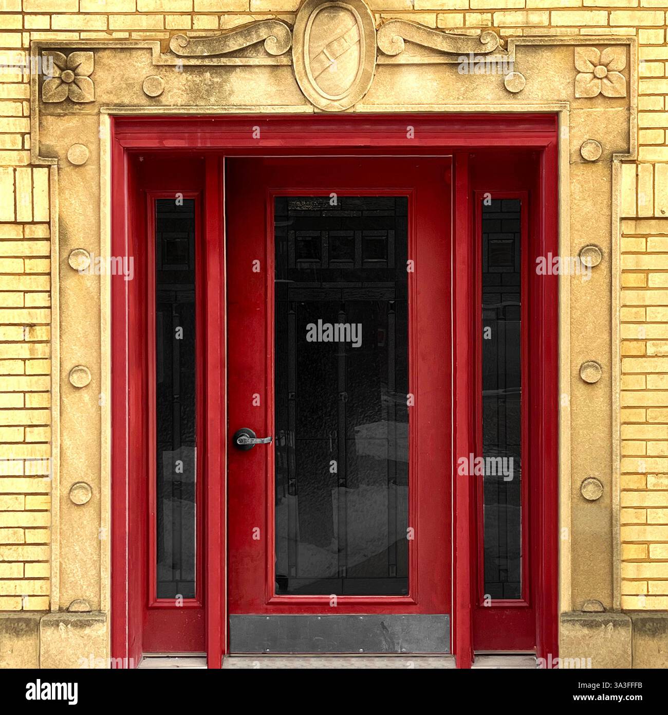 Roter Eingang, eingerahmt von komplizierten Steindetails auf einem historischen gelben Backsteingebäude in Chicago. Stockfoto