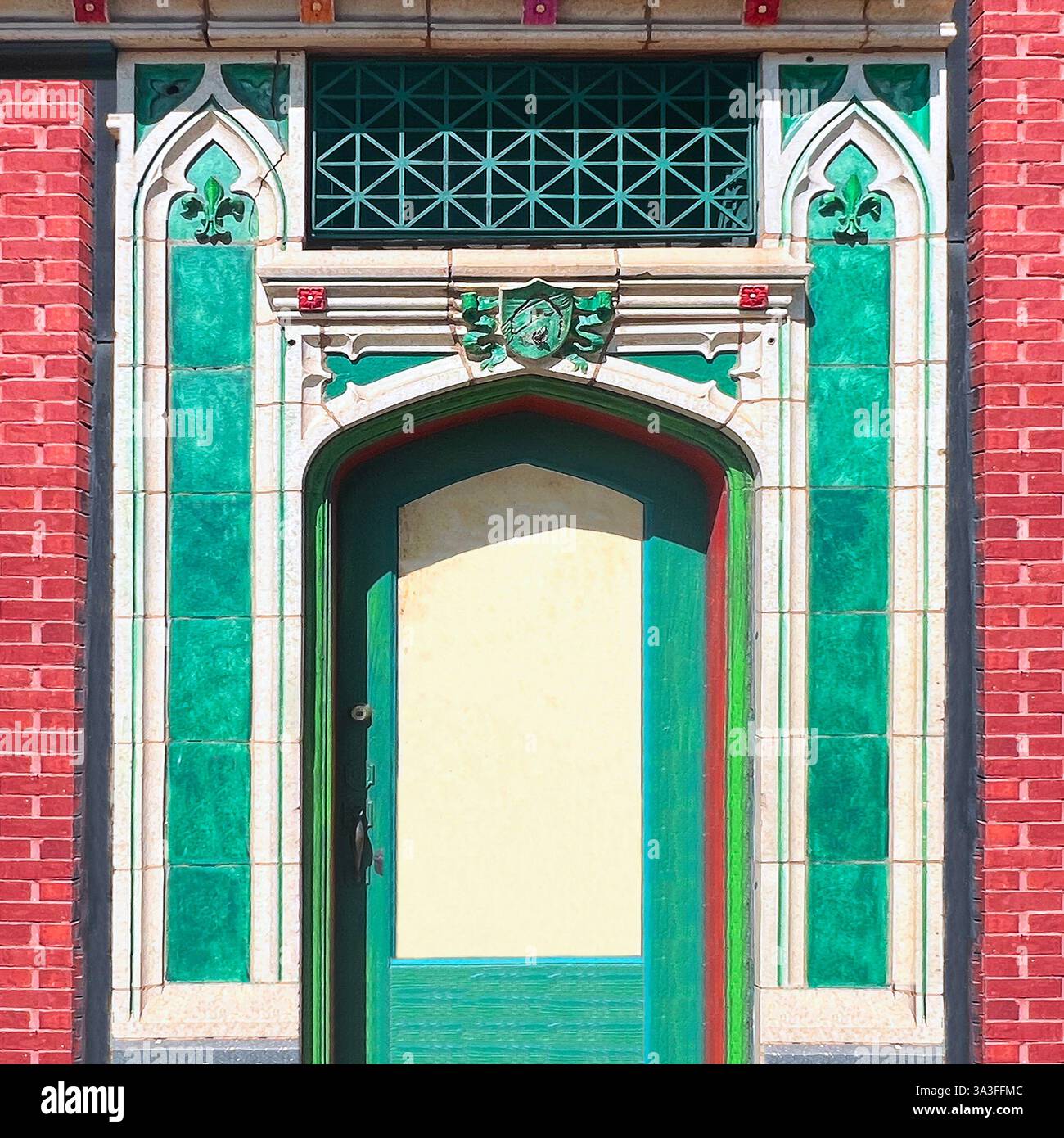 Farbenfrohe grüne Tür im gotischen Stil, eingerahmt von kunstvollen Fliesen und roten Backsteinen an einem historischen Gebäude in Chicago - Smartphone-aufgenommenes Stockfoto