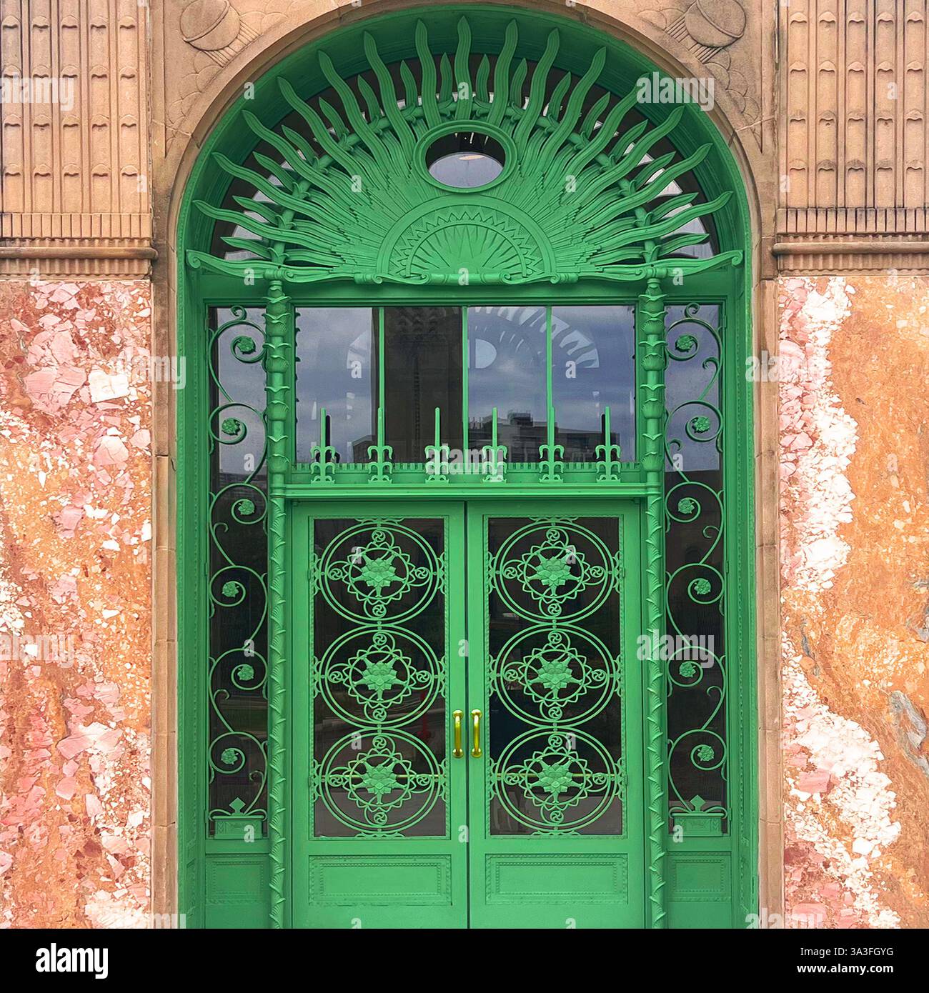 Art déco-Tür mit aufwändigem schmiedeeisernem, raffiniertem Sonnenschliff in einem großen bogenförmigen Eingang einer Bibliothek in Chicago. - Smartphone-aufgenommenes Stockfoto