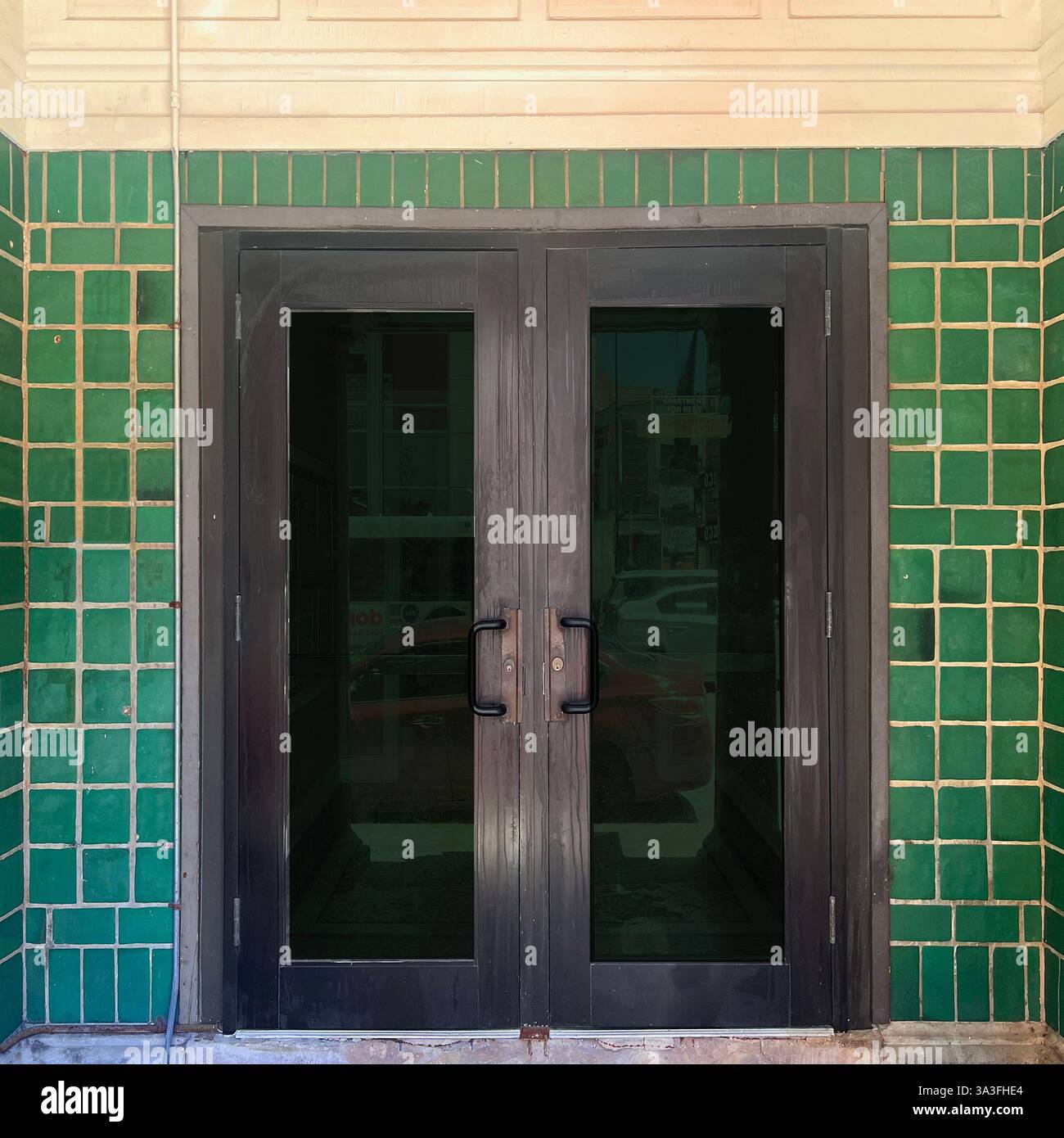 Der Eingang befindet sich in einer markanten, grün gefliesten Fassade, die den traditionellen architektonischen Charme in einer urbanen Umgebung widerspiegelt. Stockfoto Der Eingang befindet sich in einer markanten, grün gefliesten Fassade, die den traditionellen architektonischen Charme in einer urbanen Umgebung widerspiegelt. Stockfoto
