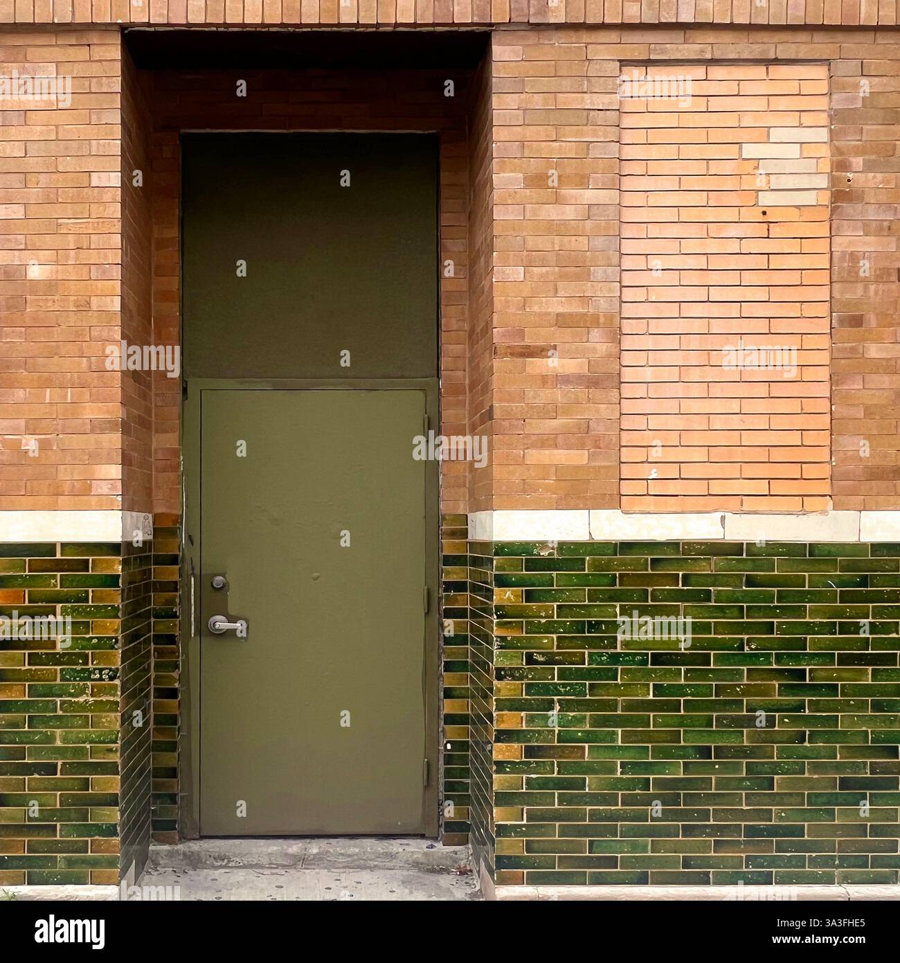 Olivgrüne Metalltür in einer alten Ziegelfassade mit grün verglasten Fliesen, die das klassische Chicago widerspiegelt. Stockfoto