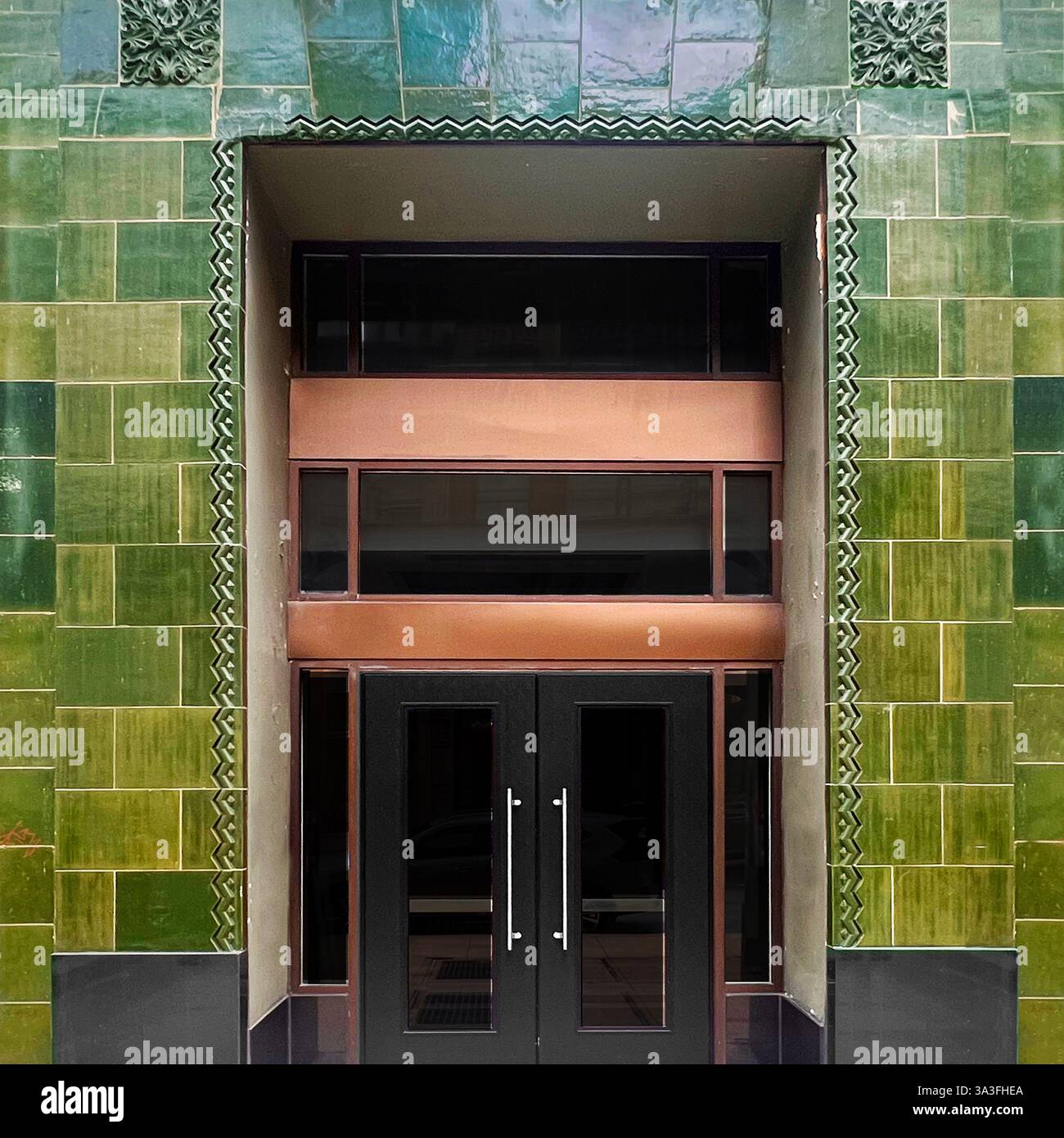 Grün gekachelter Art déco-Eingang mit Kupferakzenten in einem historischen Gebäude in Chicago. - Smartphone-aufgenommenes Stockfoto