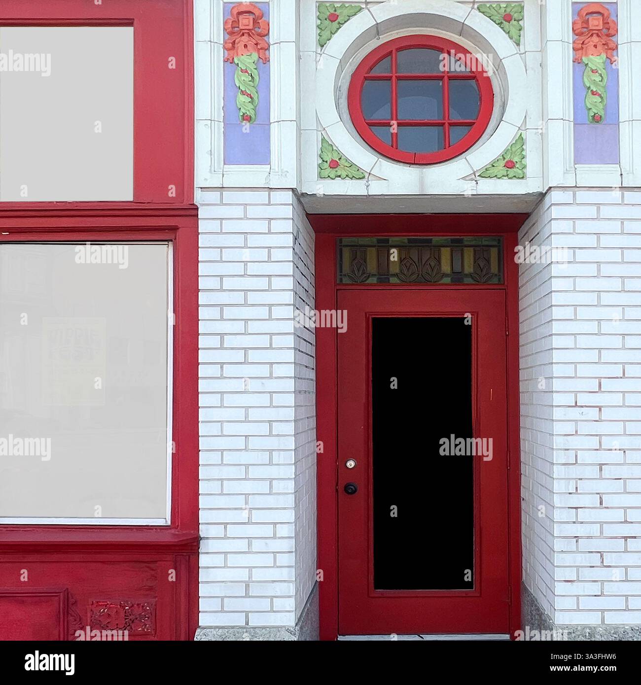 Rote Tür in einem historischen weißen Backsteingebäude, geschmückt mit bunten dekorativen Fliesen und einem runden Heckfenster in Chicago - Smartphone-aufgenommenes Stockfoto