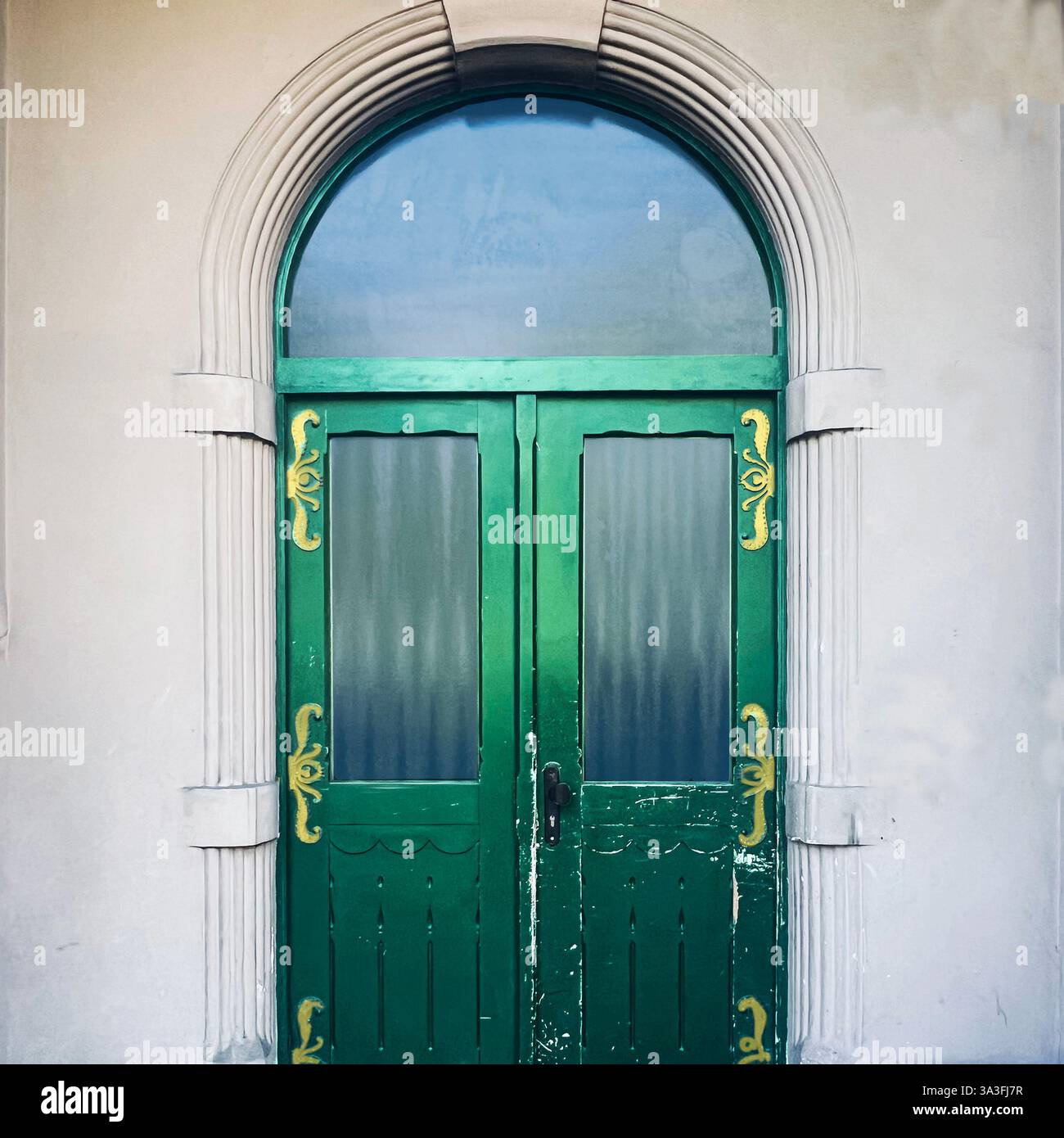 Eine elegante grüne Holztür mit goldenen Details in einem bogenförmigen Steinrahmen spiegelt den historischen architektonischen Charme in Kraków, Polen, wider Stockfoto