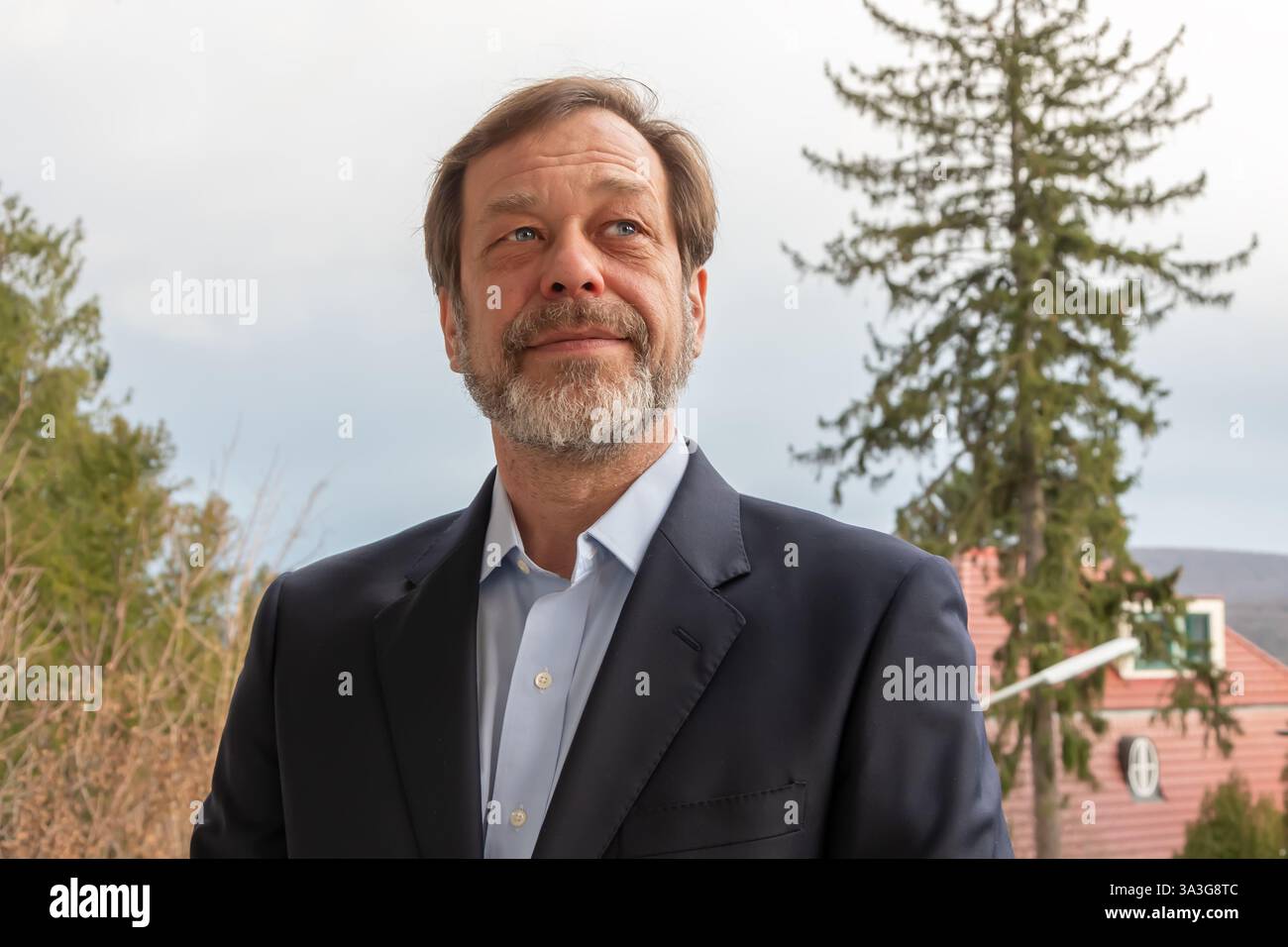 Ein bärtiger Mann im Anzug lächelt vor dem Hintergrund der Natur und schafft eine Atmosphäre der Positivität Stockfoto