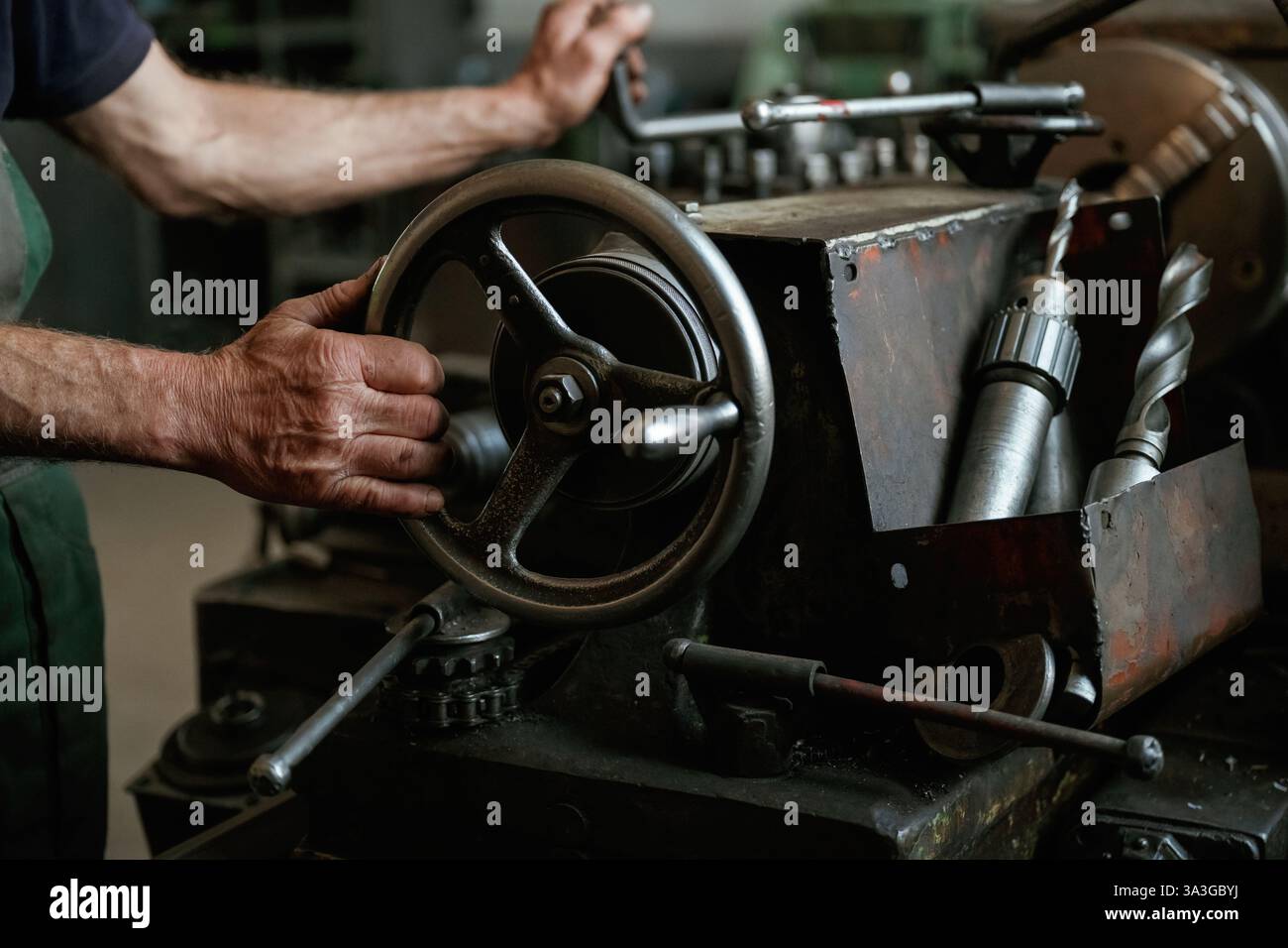 Nahaufnahme der Hände des Arbeiters, der Industriemaschinen in der Werkstatt bedient. Stockfoto