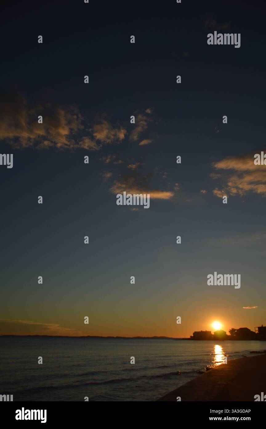 Atemberaubender Sonnenuntergang über Privlaka, Kroatien, mit leuchtenden Farbtönen, die sich auf die ruhige Adria spiegeln und eine ruhige Küstenlandschaft schaffen. Stockfoto