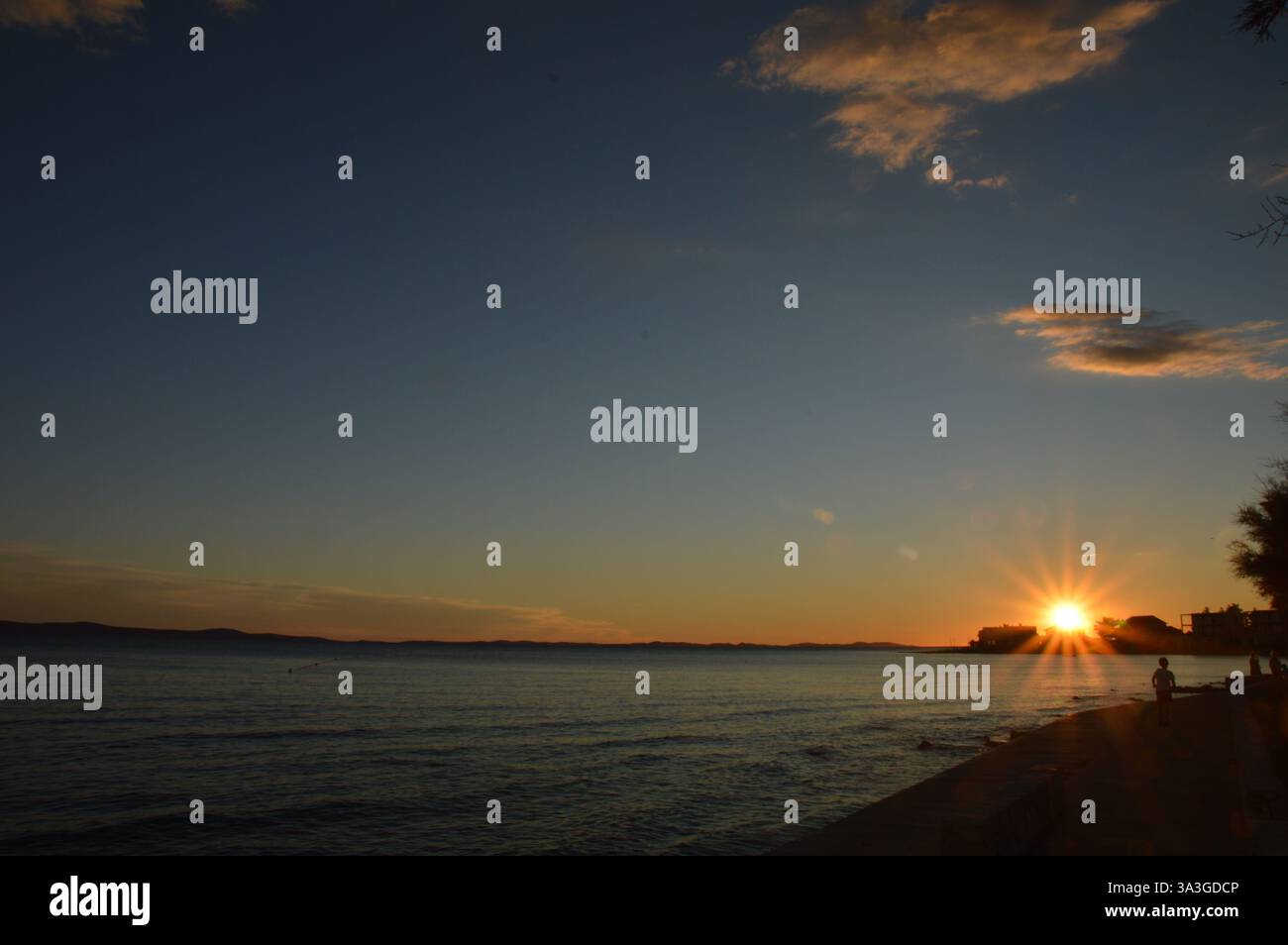 Atemberaubender Sonnenuntergang über Privlaka, Kroatien, mit leuchtenden Farbtönen, die sich auf die ruhige Adria spiegeln und eine ruhige Küstenlandschaft schaffen. Stockfoto